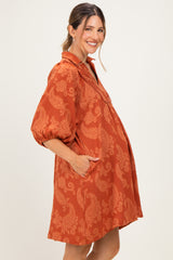woman wearing a rust-colored maternity dress with puff sleeves and pockets, highlighting her baby bump