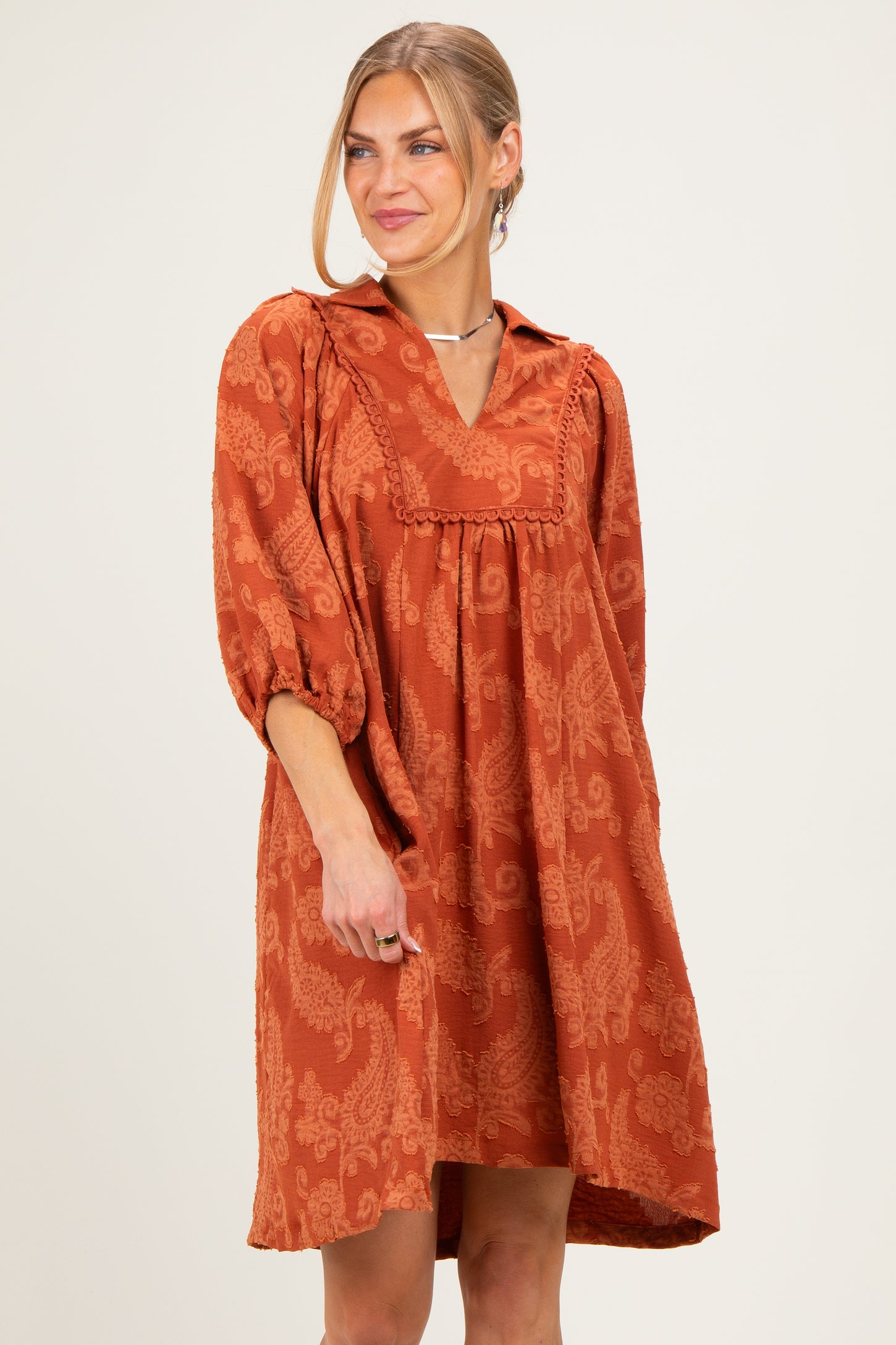woman wearing an orange paisley print dress with a collar and puff sleeves