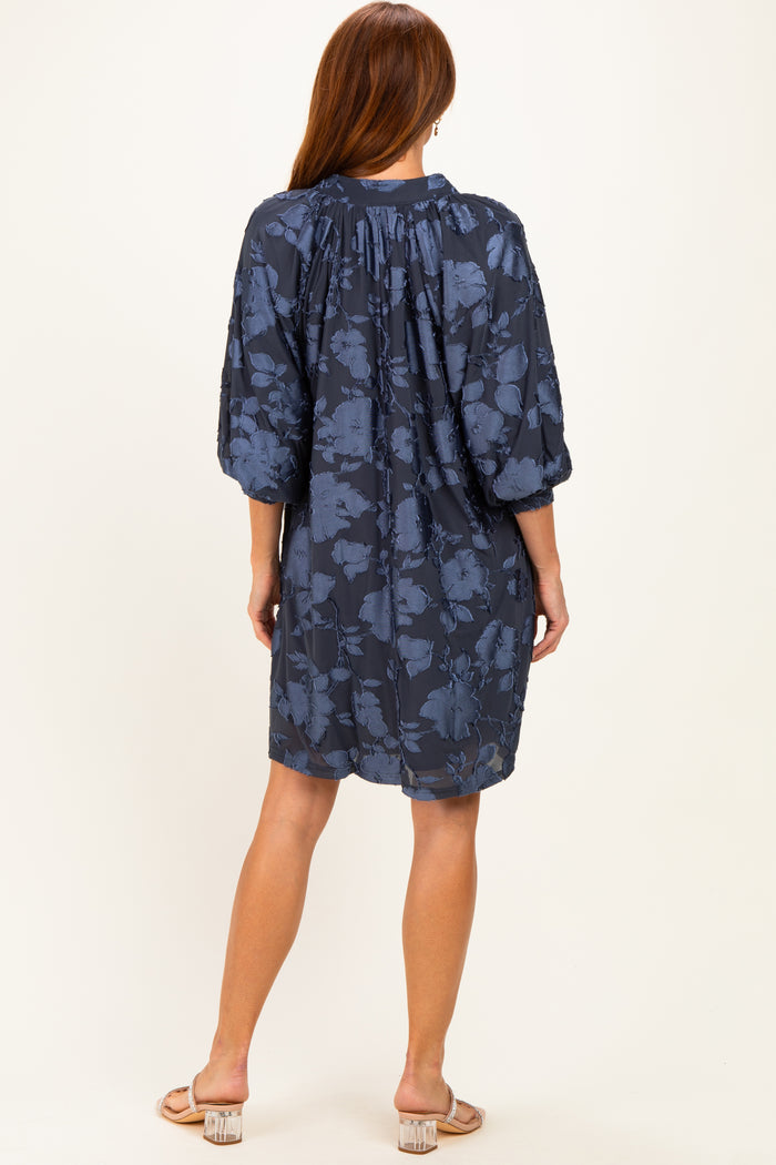 woman wearing a navy blue floral short dress with three-quarter puff sleeves, shown from the back