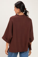woman wearing a brown oversized knit top with rolled sleeves and back neckline detail