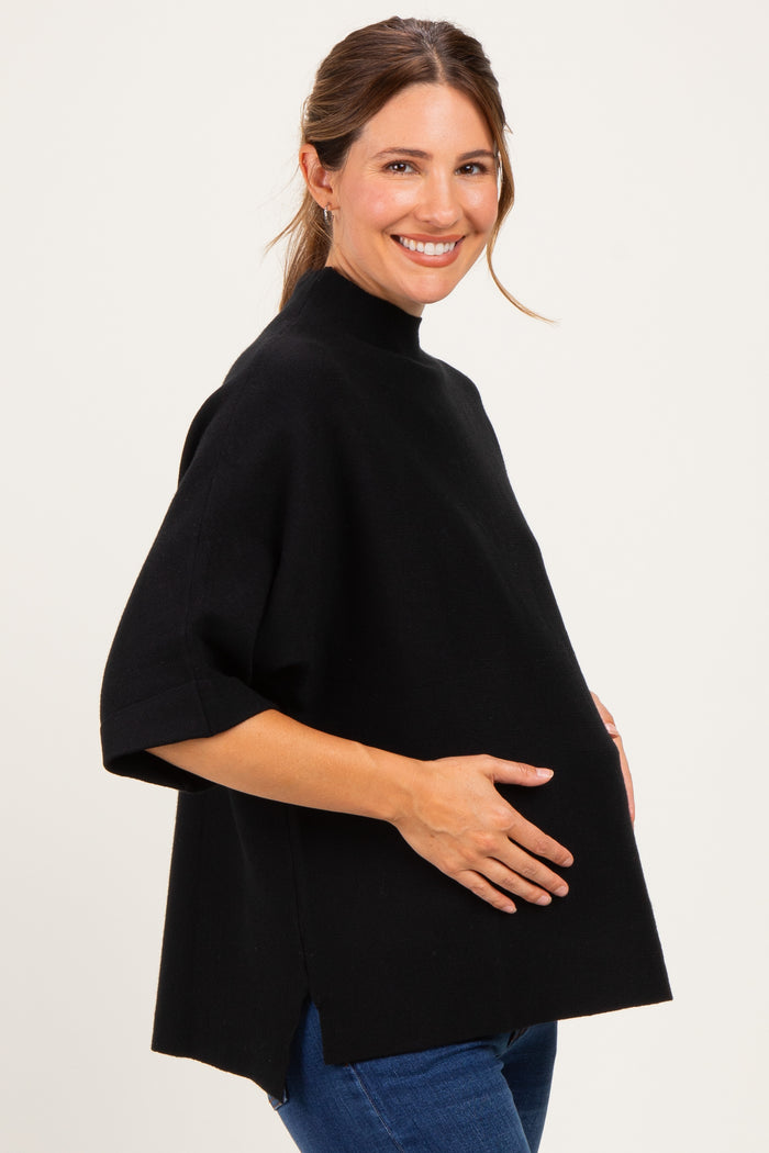 woman wearing a black maternity poncho top with a high neckline and a visible baby bump