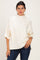 woman wearing a cream oversized pullover with a high neckline and rolled sleeves paired with blue jeans