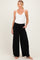 woman wearing a white lace trim maternity tank top and black wide-leg maternity pants with pockets