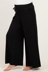woman wearing black wide-leg maternity pants with an elastic waistband and drawstring detail