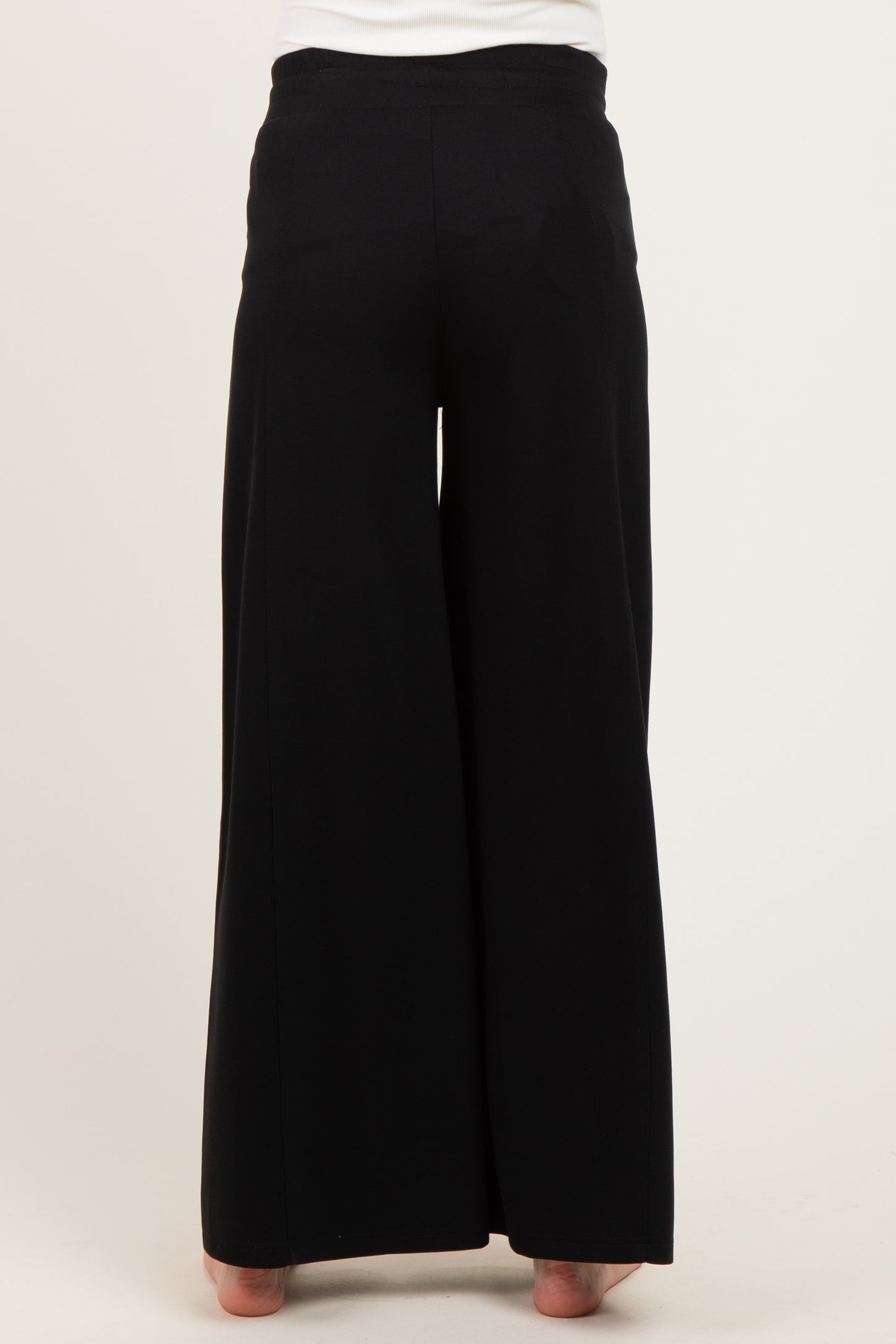 maternity wear black wide-leg pants displayed from the back, model wearing them with bare feet