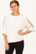 woman wearing a cream oversized sweatshirt with sheer detailing on the sleeves and paired with black leggings