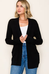 woman wearing a black open-front cardigan with pockets and styled with a white top and blue jeans