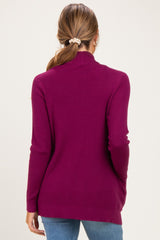 woman wearing a plum long sleeve maternity sweater with a mock neck and side slits, seen from the back