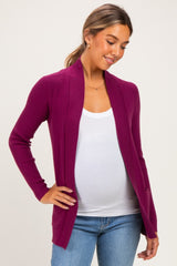 woman wearing a magenta long sleeve maternity cardigan over a white tank top and showing her baby bump