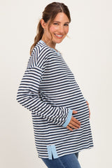 woman wearing a navy and white striped maternity top with a blue trim and holding her baby bump