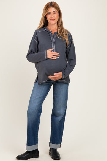 woman wearing a navy blue maternity long sleeve top and holding her baby bump, paired with relaxed fit jeans