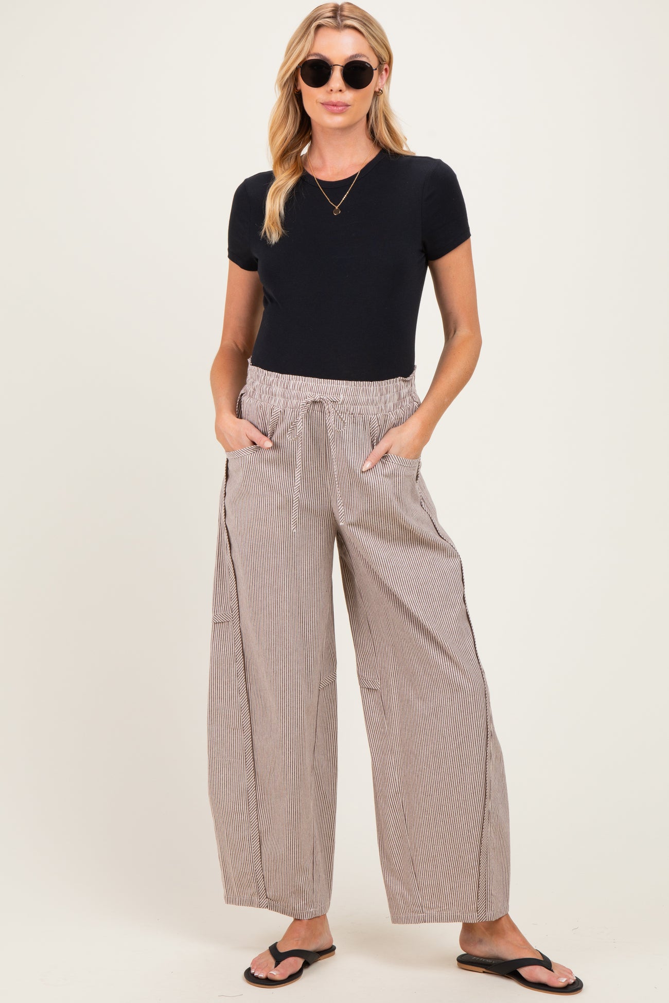 woman wearing a black short sleeve maternity top and relaxed striped maternity pants with pockets