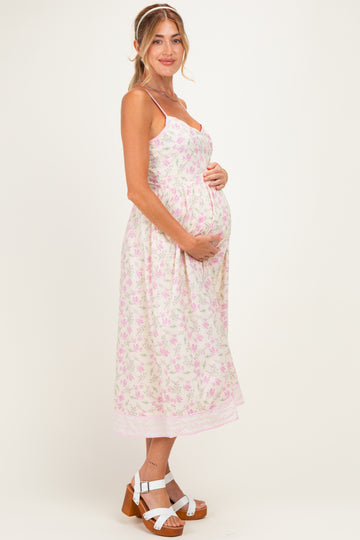 woman wearing a floral light pink maternity dress and holding her baby bump