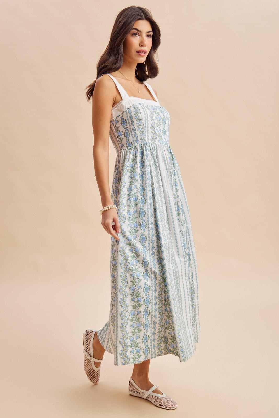 woman wearing a light blue and white floral maxi dress with a fitted bodice and spaghetti straps