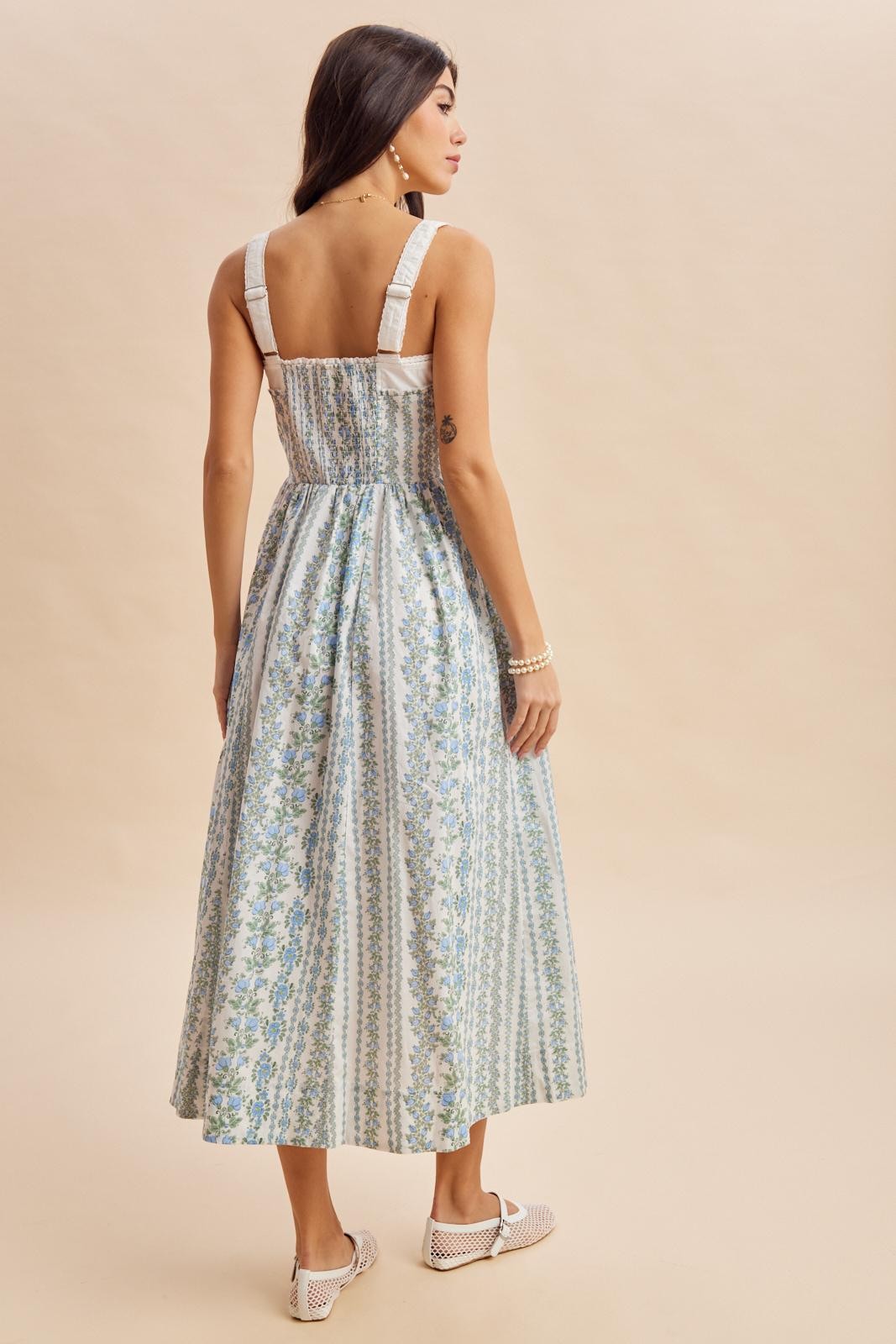 woman wearing a blue and white floral maxi dress with a smocked back and wide straps, seen from the back