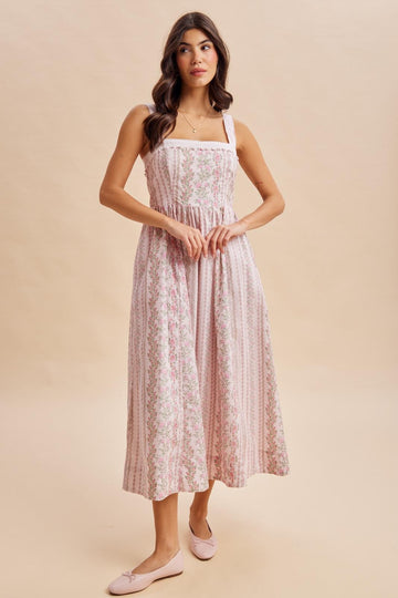 woman wearing a pink floral midi dress with square neckline and shoulder straps, standing on a beige background