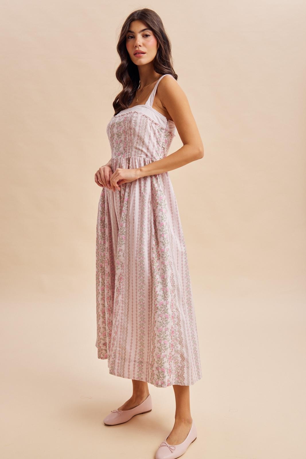 woman wearing a pink floral maxi dress with spaghetti straps and a fitted bodice