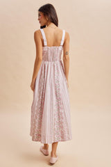 woman wearing a back view of a pink floral maxi dress with adjustable straps and a smocked bodice