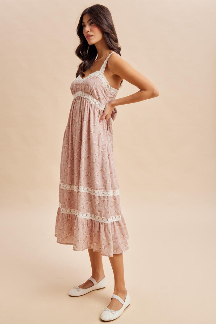 woman wearing a pink floral midi dress with lace trim and adjustable straps, styled with white flats