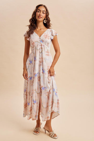 woman wearing a cream floral maxi dress with ruffle sleeves and a cinched waist