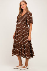 woman wearing a brown polka dot maternity dress with a v-neck and flutter sleeves, showing her baby bump