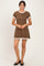 woman wearing a brown polka dot dress with short sleeves and ruffled hem