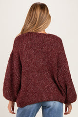 woman wearing a burgundy chunky knit maternity sweater with balloon sleeves, seen from the back