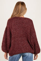 woman wearing a burgundy chunky knit maternity sweater with balloon sleeves, seen from the back
