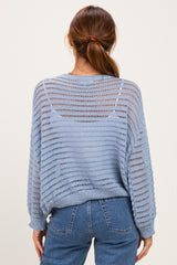 woman wearing a light blue open-knit sweater with a relaxed fit and long sleeves, styled with high-waisted jeans