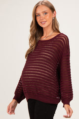 woman wearing a burgundy maternity sweater with open knit design and visible baby bump
