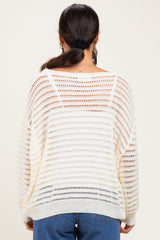 woman wearing a cream open-knit sweater with a loose fit and striped pattern, seen from the back