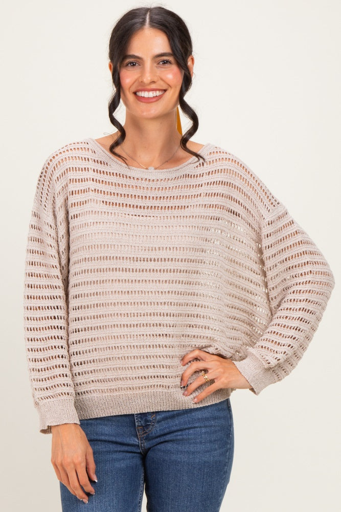 woman wearing a beige knitted sweater with horizontal stripes and loose fit, paired with blue jeans