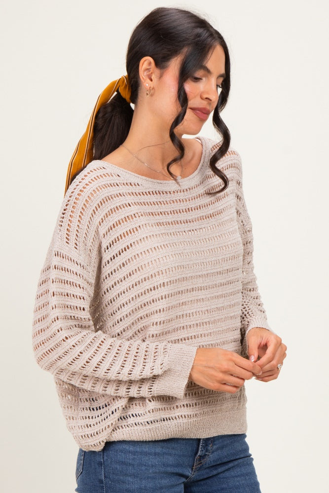 woman wearing a light beige open-knit sweater with a relaxed fit and long sleeves