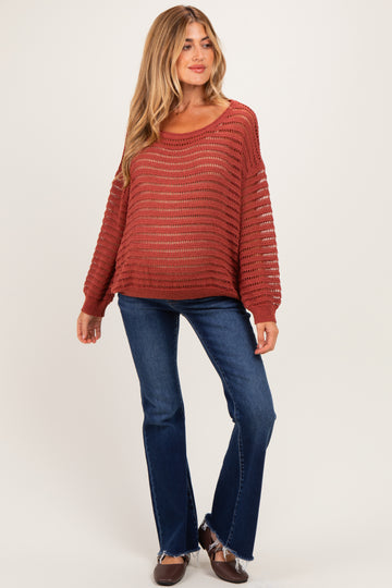 woman wearing a rust striped maternity sweater with a loose fit, paired with flare jeans and brown shoes