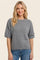woman wearing a gray short sleeve sweater paired with light blue jeans