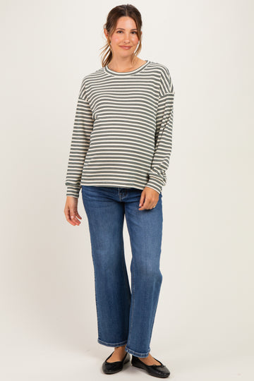 woman wearing a gray and white striped maternity top with long sleeves and blue wide-leg jeans, showing her baby bump