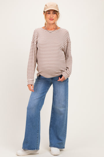 woman wearing a striped brown and cream maternity top and wide-leg blue jeans, showing off her baby bump