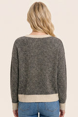 woman wearing a black and cream striped sweater viewed from the back, styled with light blue jeans