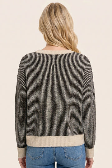 woman wearing a black and cream striped sweater viewed from the back, styled with light blue jeans