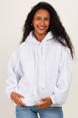 woman wearing a light grey maternity hoodie with a relaxed fit and holding her baby bump