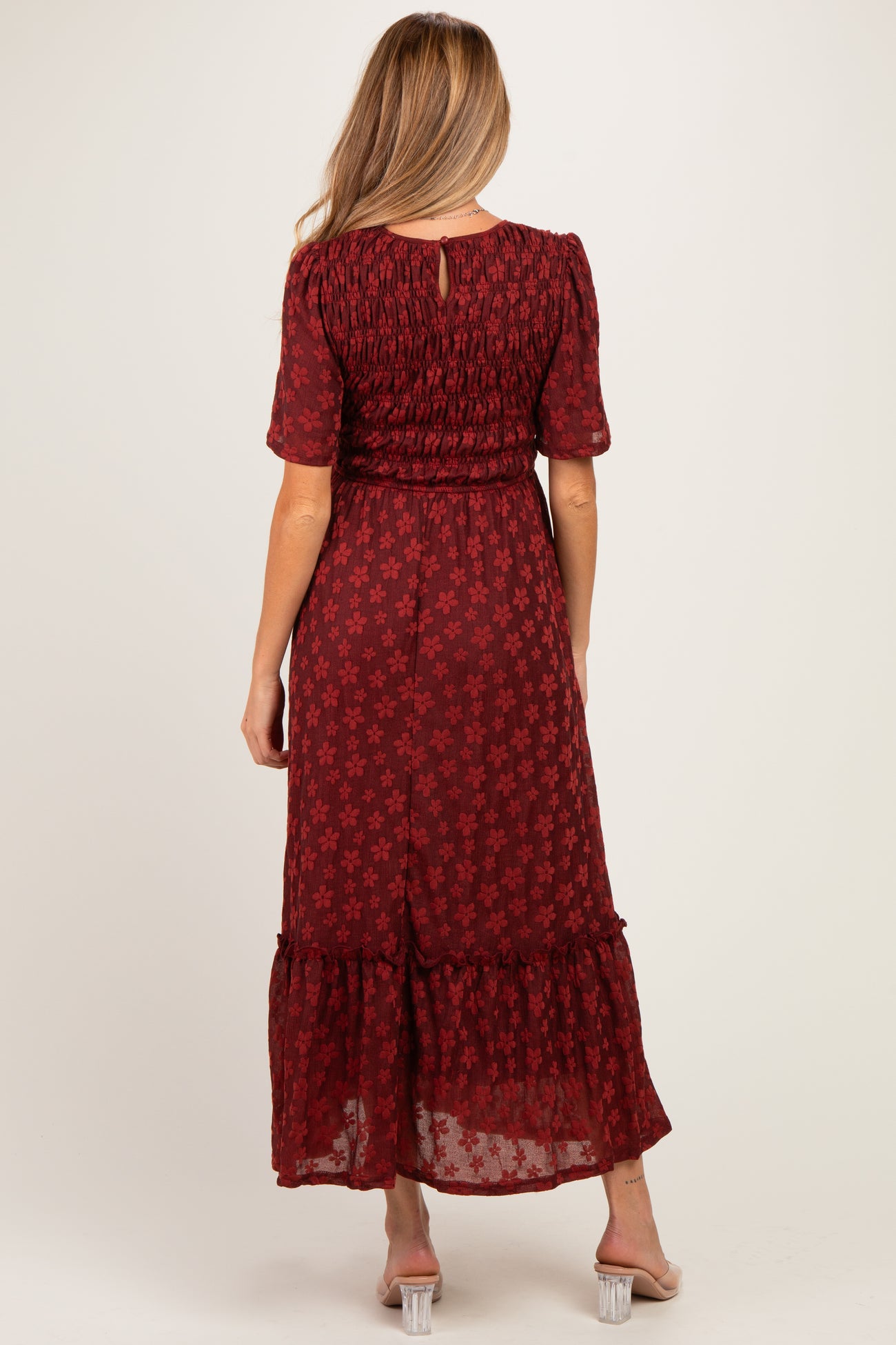 woman wearing a burgundy floral maternity maxi dress with short sleeves and smocked bodice, showing a baby bump