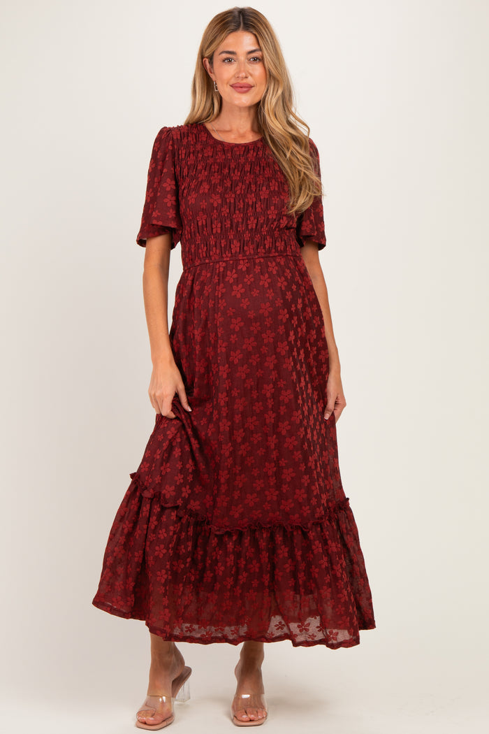 woman wearing a burgundy floral maternity dress with short sleeves and a tiered skirt, styled for a comfortable fit