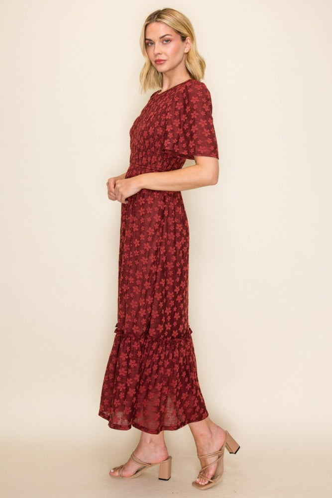 woman wearing a burgundy floral midi dress with short sleeves and a ruffled hem