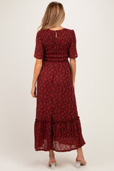 woman wearing a burgundy floral maternity maxi dress with short sleeves and smocked bodice, showing a baby bump