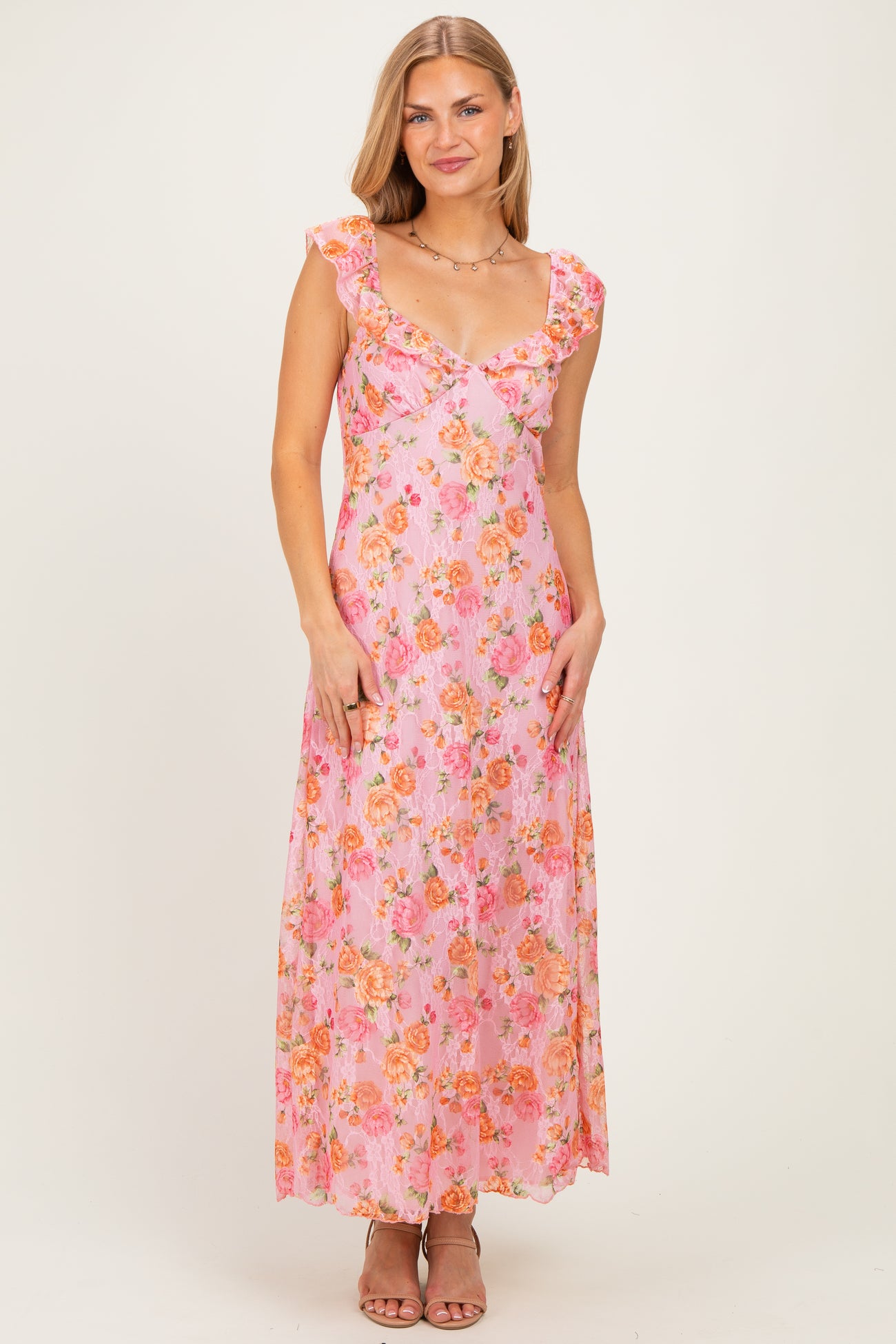 woman wearing a pink floral maxi dress with ruffled straps and a deep v-neckline