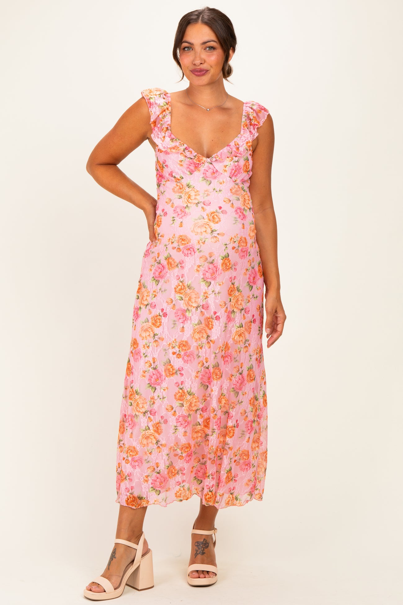 woman wearing a pink floral maternity dress with ruffled sleeves and a visible baby bump