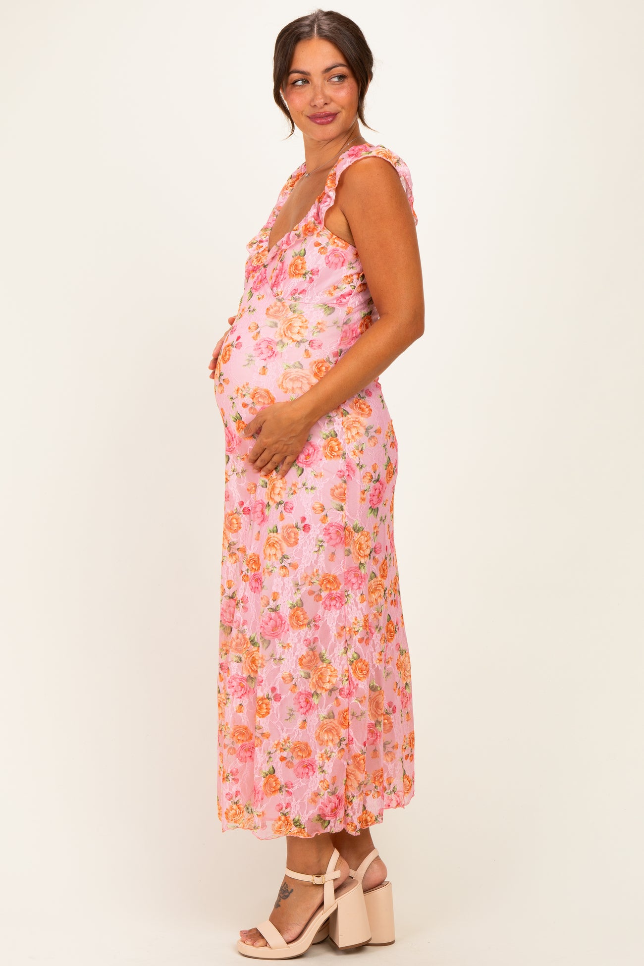 woman wearing a pink floral maternity dress with ruffled sleeves and a visible baby bump