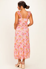 woman wearing a pink floral maternity dress with ruffled straps, showing a baby bump from the back