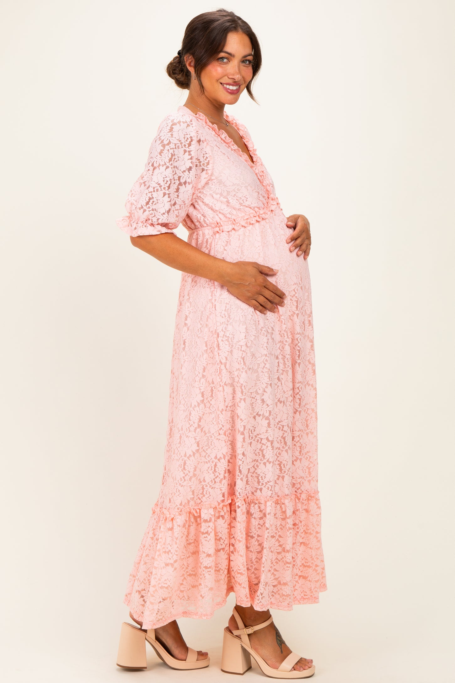 woman wearing a pink lace maternity maxi dress, highlighting her baby bump with a tiered skirt and short sleeves