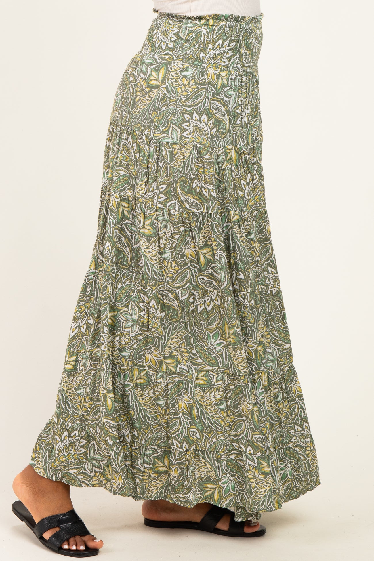 woman wearing a green bohemian maxi skirt with an intricate floral pattern and smocked waistband